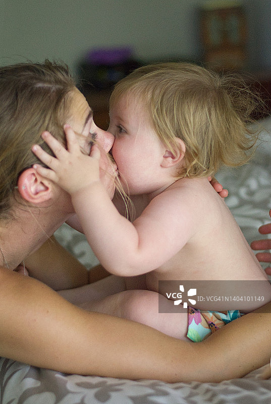 年轻的母亲亲吻婴儿图片素材
