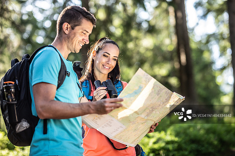一对旅游夫妇正在纸地图上寻找一条森林路线图片素材