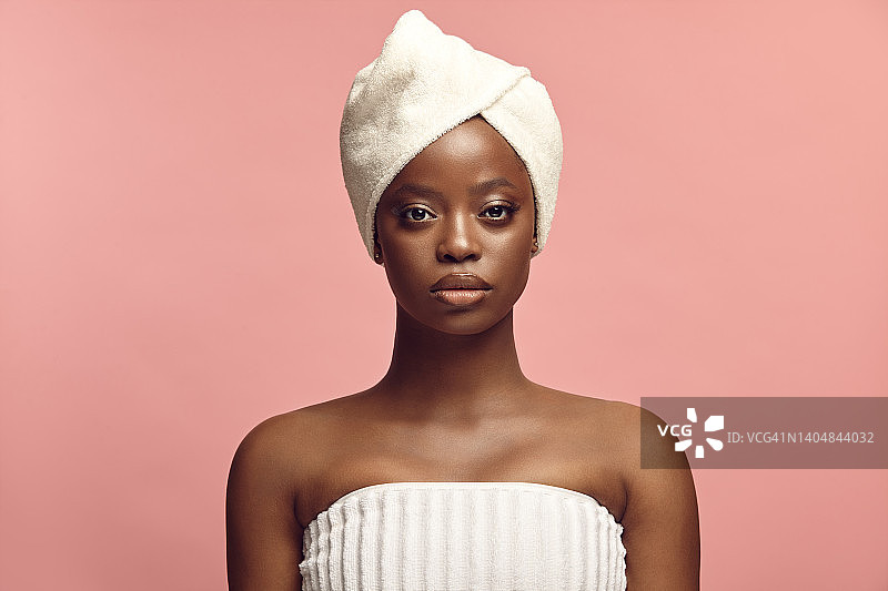头像前肖像美丽的黑色皮肤妇女在温泉浴巾在粉红色的背景与免费复制空间。图片素材