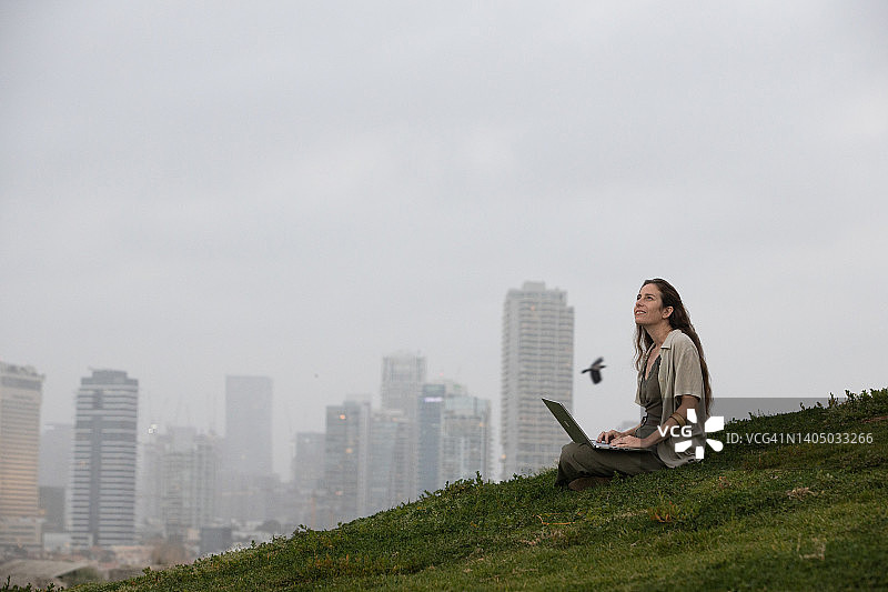 在城市风景前用笔记本电脑工作的女人图片素材