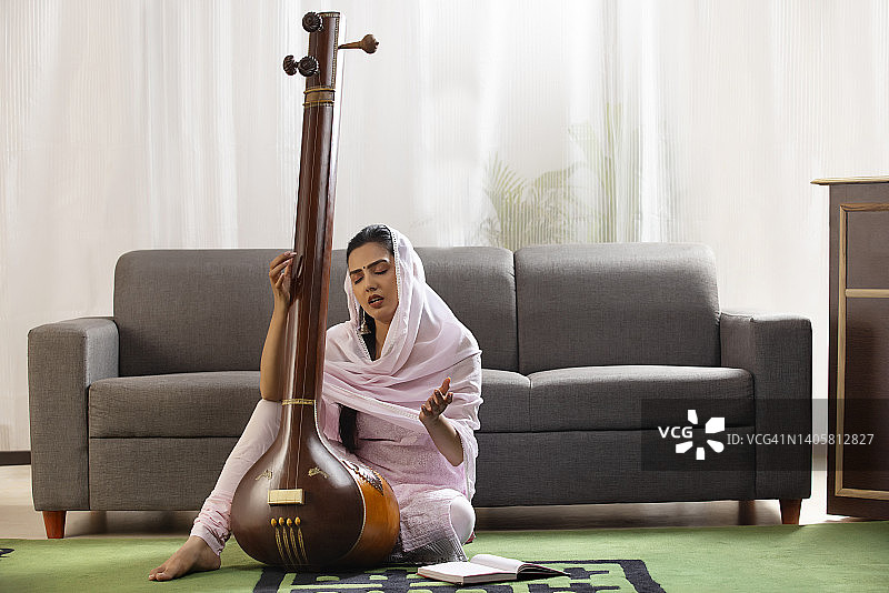 年轻的古典女歌手在家里弹奏坦普拉图片素材