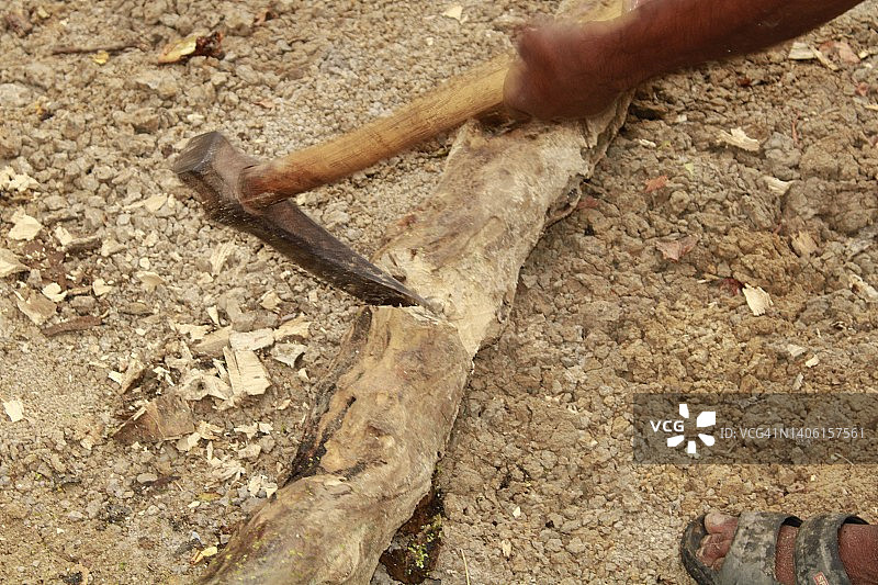 阳光灿烂的日子，印度中年体力劳动者用斧头砍柴。图片素材