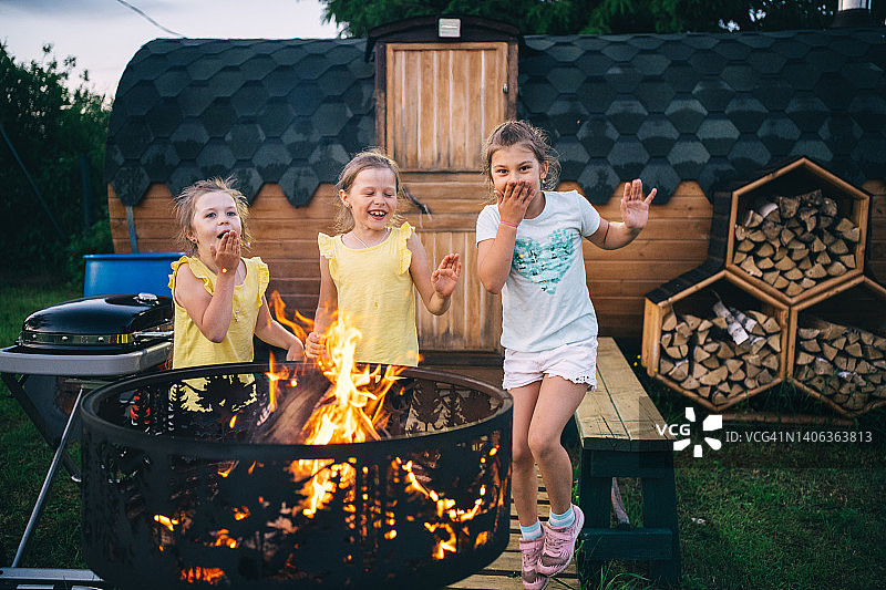 孩子们在户外小屋的篝火旁玩耍图片素材