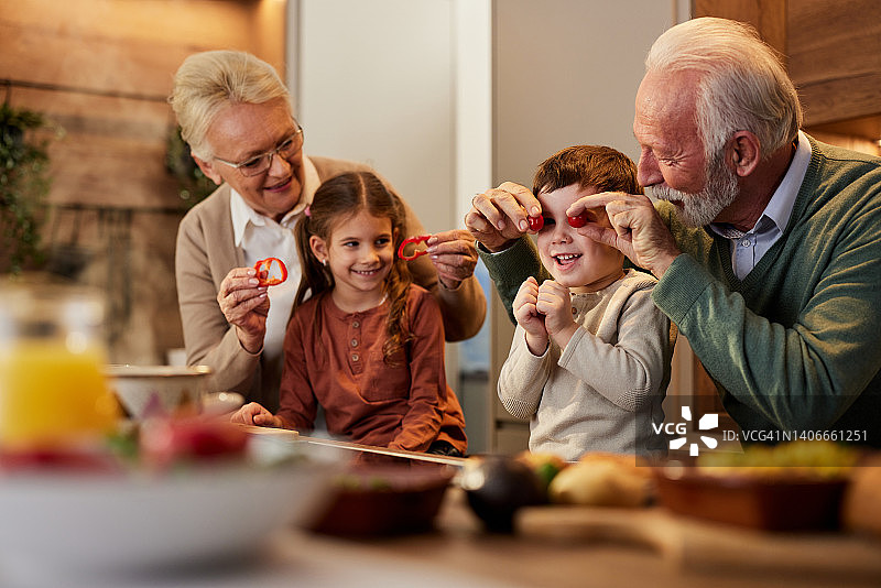 快乐的祖父母和他们的孙子孙女在厨房里玩得很开心。图片素材