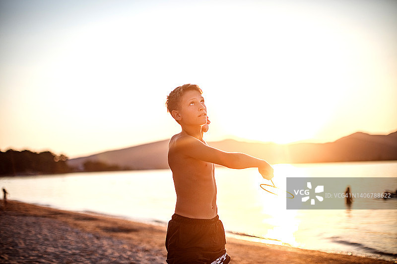 日落时分，一个男孩在海滩上打羽毛球图片素材