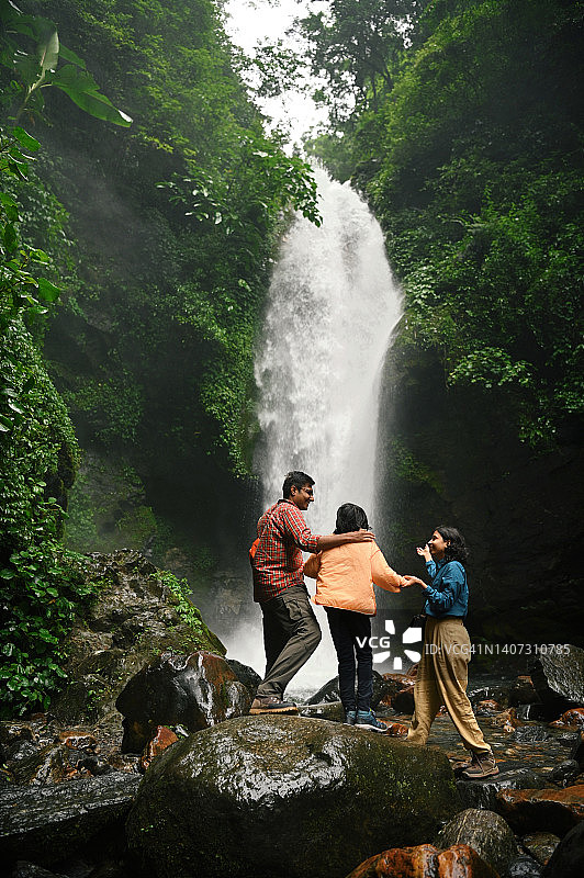 一个家庭欣赏雄伟的瀑布的后视图图片素材