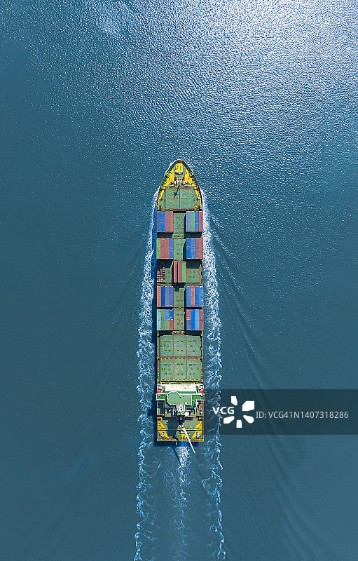 高空俯视，大型集装箱船黄色船首正高速行驶在海面上。集装箱船进出口、物流、国际运输业务。图片素材
