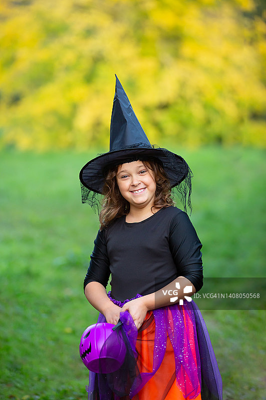 万圣节孩子,孩子。在秋天的公园里，微笑的女孩穿着女巫服装，戴着橙色和黑色的气球图片素材