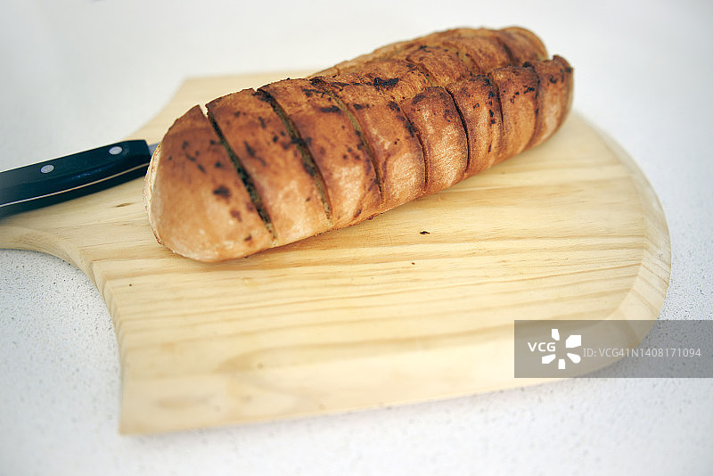 硬皮的酸面团蒜蓉面包放在木板上。图片素材