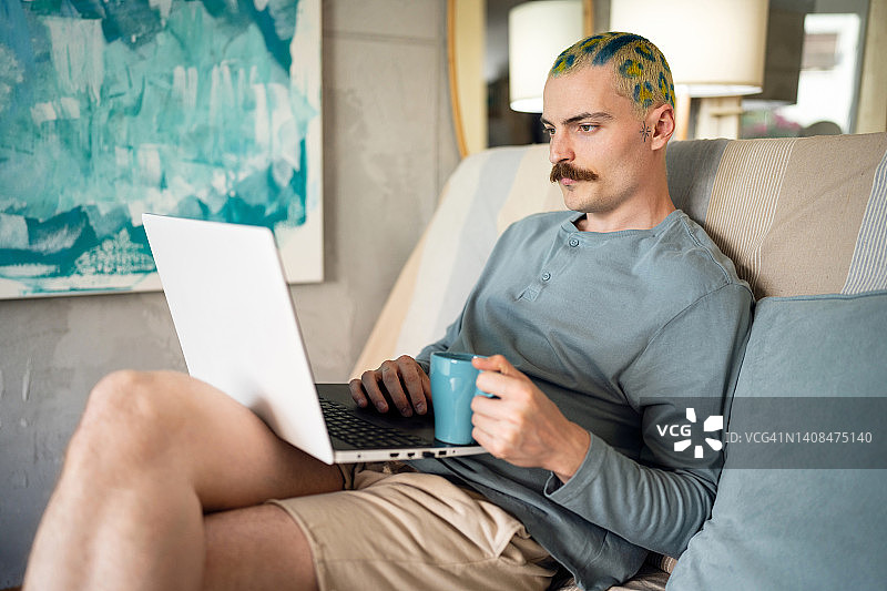 现代男性自由职业者，染着有趣的头发，在笔记本电脑上工作图片素材