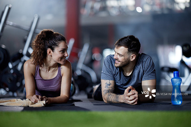 一对快乐的运动情侣在体育馆里的休息时间聊天。图片素材