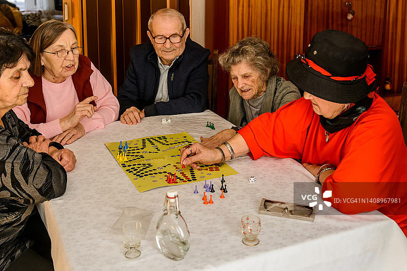在一次社交聚会上，一群年长的人正在玩ludo游戏，玩得很开心。图片素材