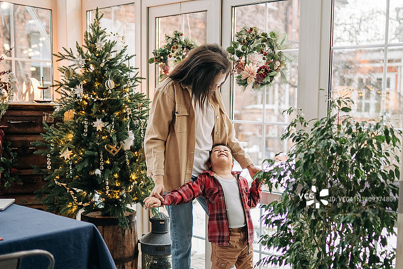 母亲和儿子在家里装饰圣诞树。家庭，节日，圣诞节的概念图片素材