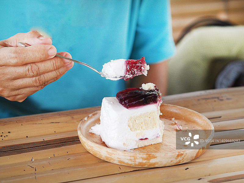 女人用叉子吃蛋糕块红丝绒与鲜奶油在木盘子图片素材