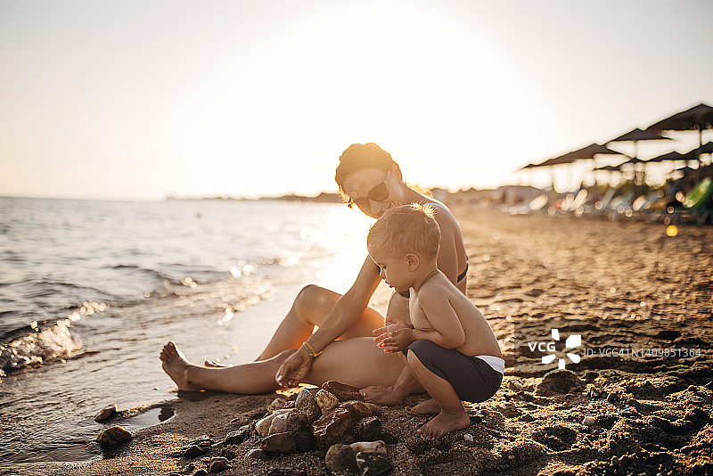 日落时分，母亲和儿子在海滩上玩耍图片素材