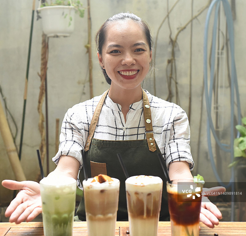 一位亚洲女服务员在咖啡店里为顾客准备饮料图片素材