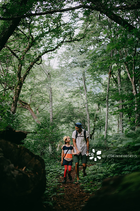 父亲和小女儿一起在森林里徒步旅行图片素材