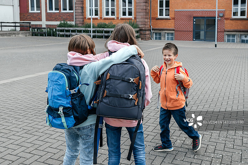 一群小学生背着书包去上学。暑假结束后，孩子们回到教室图片素材