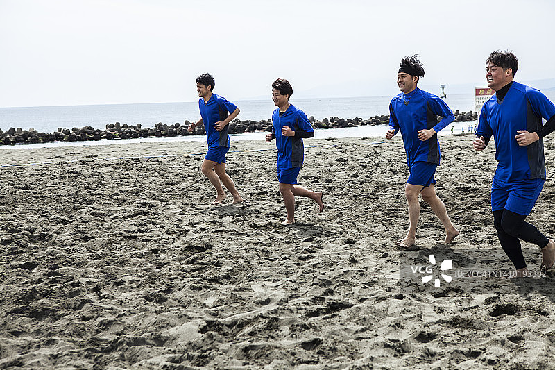 四名球员在沙滩球场慢跑图片素材