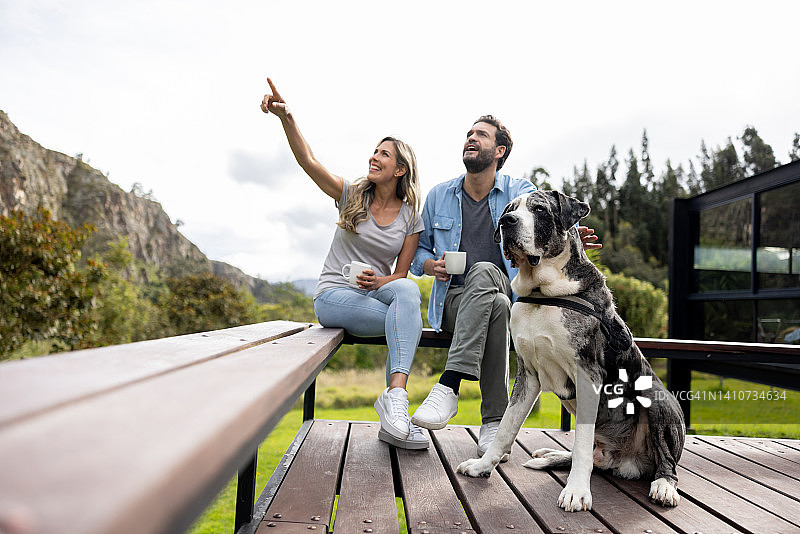一对幸福的夫妇在阳台上和他们的狗一起喝咖啡图片素材