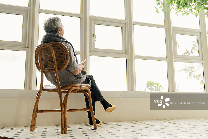 孤独的老年男子男子享受望向窗外在家里的视野从他的窗口，侧视图的老年男子谁有慢性疾病阿尔茨海默病坐在客厅图片素材