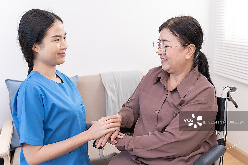 家庭保健护士女性握住老年女性老年病人的手护理。图片素材