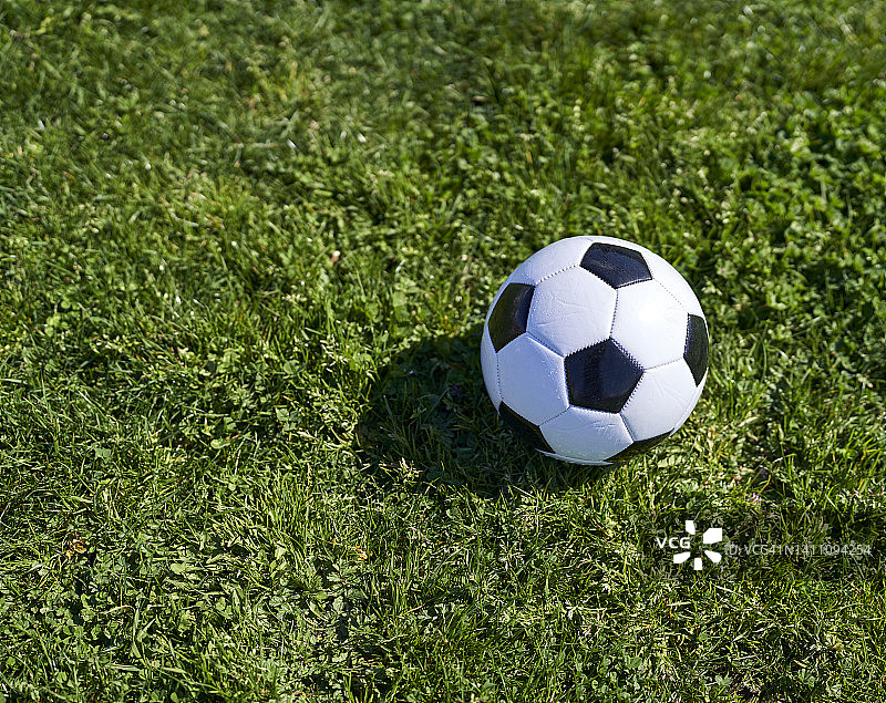经典的足球休息在草地上的一个大公园在一个孩子们的游戏在周日下午。图片素材