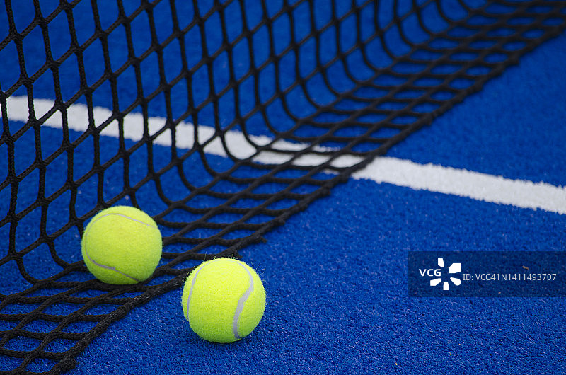 蓝色的球拍网球场，两个球靠近网图片素材