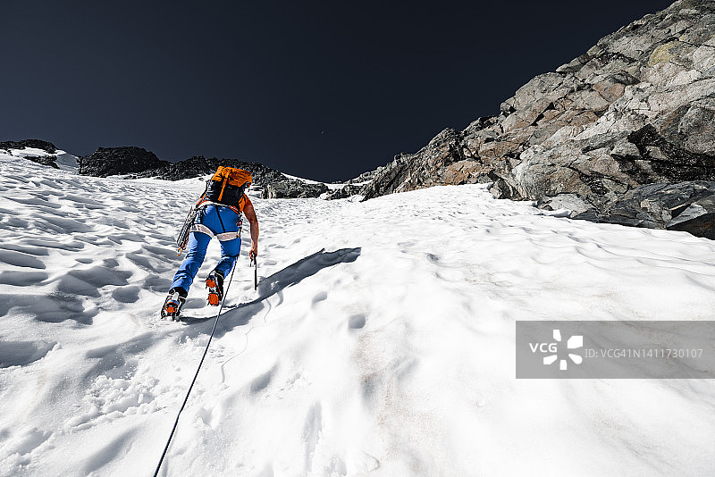 在不列颠哥伦比亚省，一名男登山者正在攀登陡峭的积雪覆盖的山峰图片素材