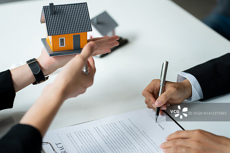 房地产经纪人建议客户在合同批准后签订合同购买房屋和土地。提供抵押贷款与家庭保险的想法。图片素材