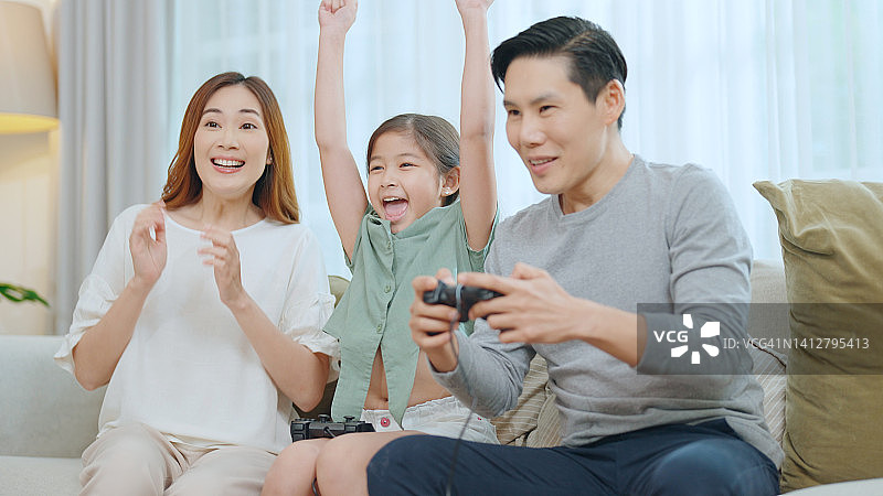 假期的早晨，一家人在家里愉快地玩电子游戏。图片素材