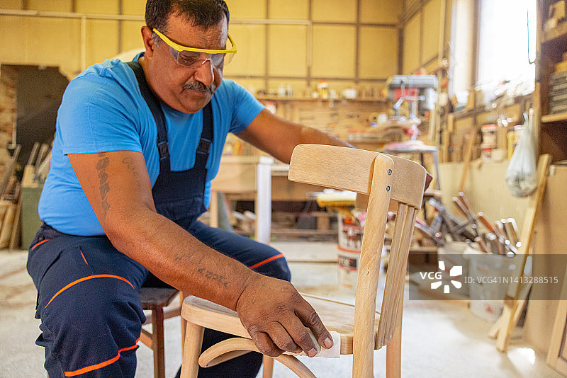 印度木匠独自在他的车间工作。他戴着安全眼镜图片素材