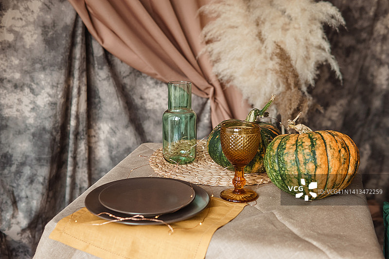 秋天的室内装饰:一张桌子上摆满了盘子、南瓜，还有一种轻松的日式潘帕斯草原。照相馆内部。一张装饰过的秋季餐桌的特写。图片素材