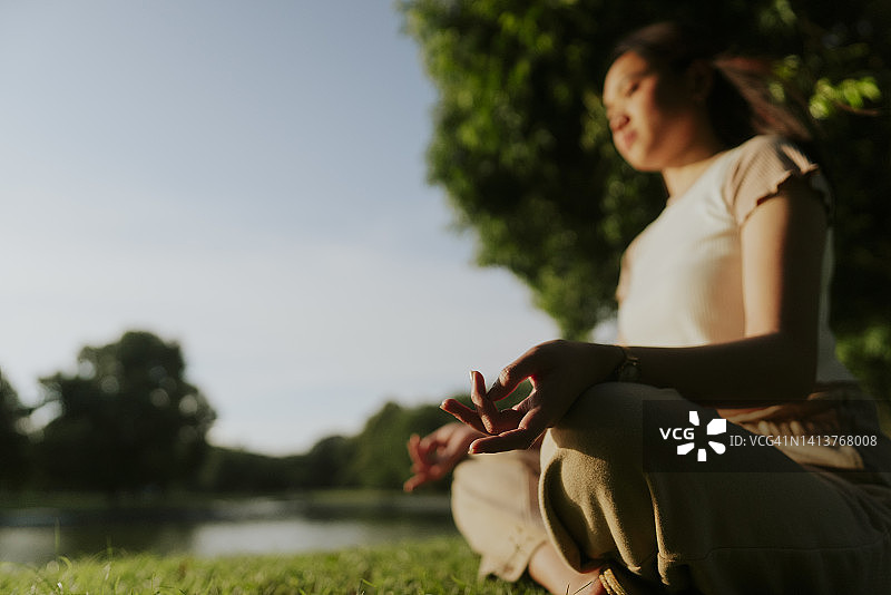 冷静亚洲少女女性练习瑜伽和冥想坐在地上呼吸在公园呼图片素材