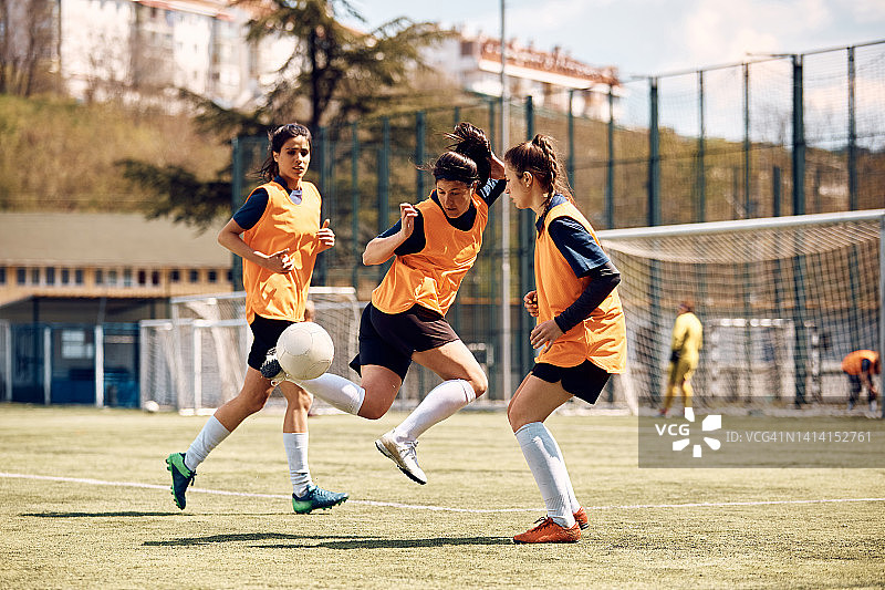 在体育场的运动训练中，熟练的女足球运动员在行动。图片素材