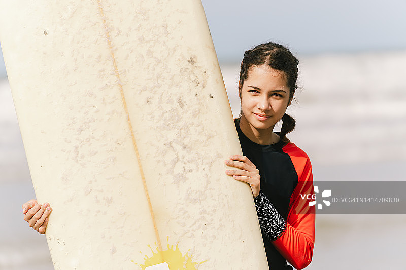 美丽的亚洲女孩拿着冲浪板微笑图片素材