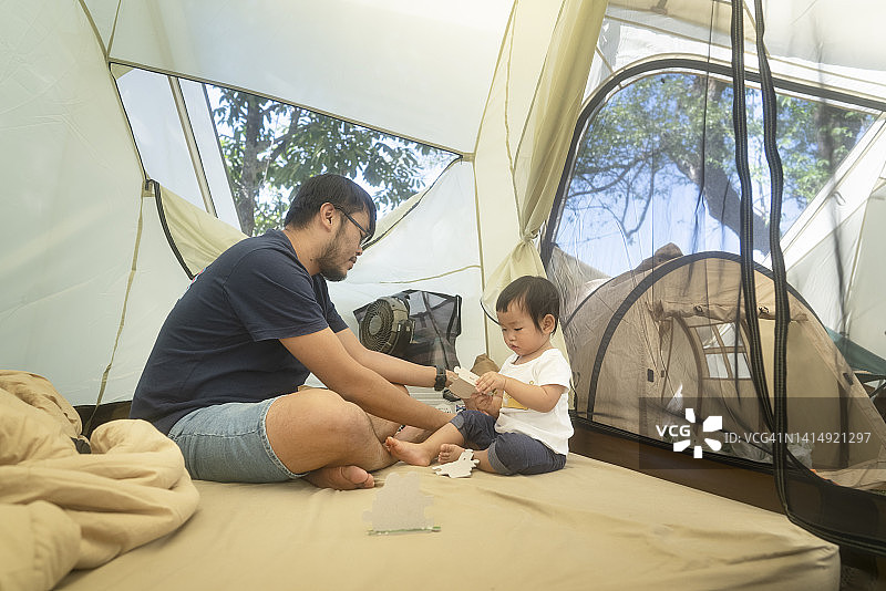 露营时间父亲花时间教和玩绘本与女儿在帐篷户外生活方式周末活动图片素材