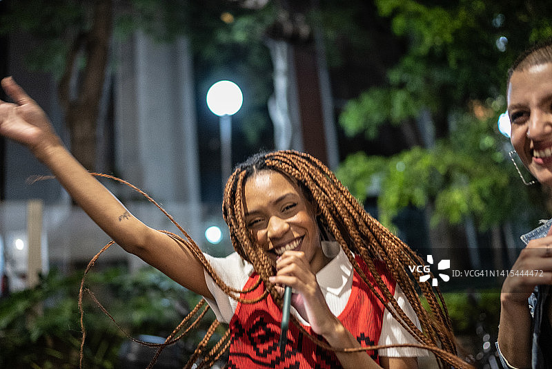 一个年轻女子的画像，晚上在街上拿着手机唱歌图片素材
