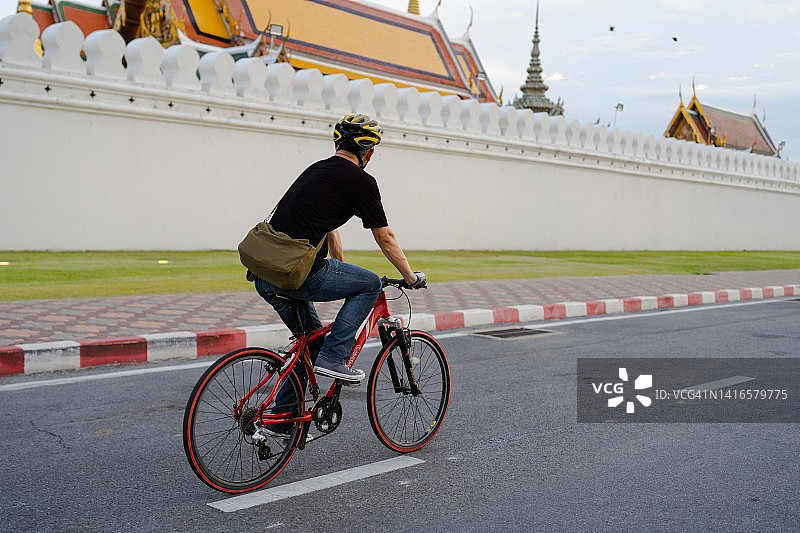 一名亚洲男子在周末骑着自行车在城市里转悠。图片素材
