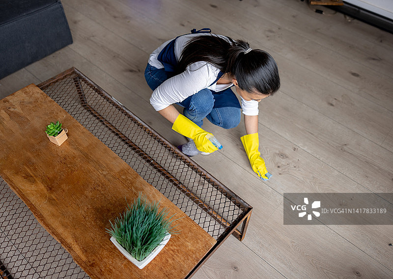 妇女在家里清理硬木地板上的一块地方图片素材
