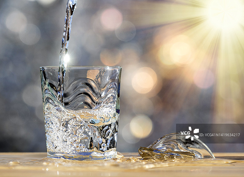 用打碎的杯子装满水，被阳光照亮。图片素材