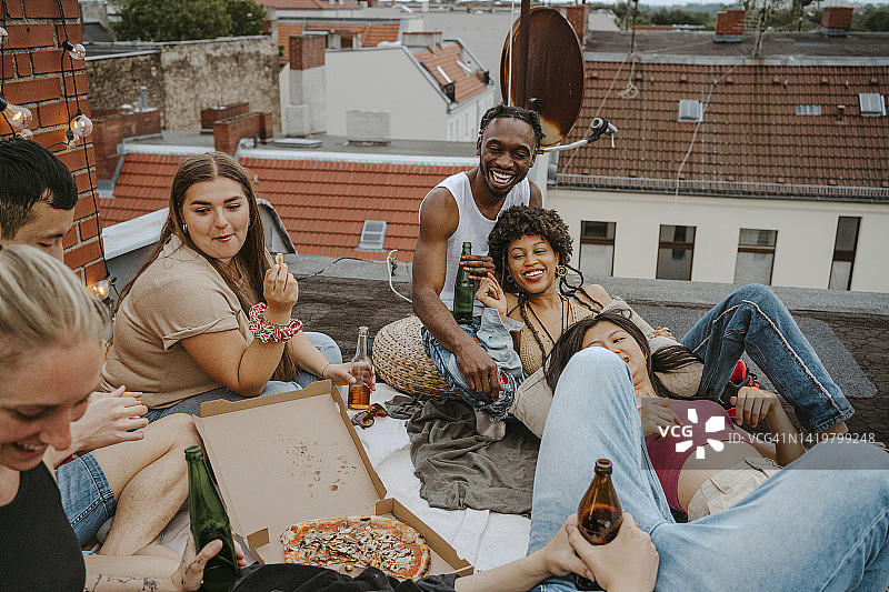 快乐的男性和女性朋友与披萨享受派对在屋顶图片素材