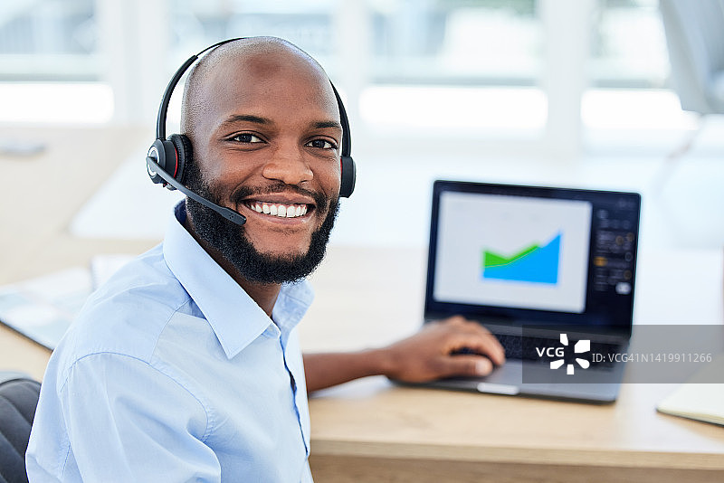呼叫中心代理、客户服务代表和销售支持人员都戴着耳机，在办公室用笔记本电脑工作。负责数据收集，市场营销和财务，一名男性操作员图片素材