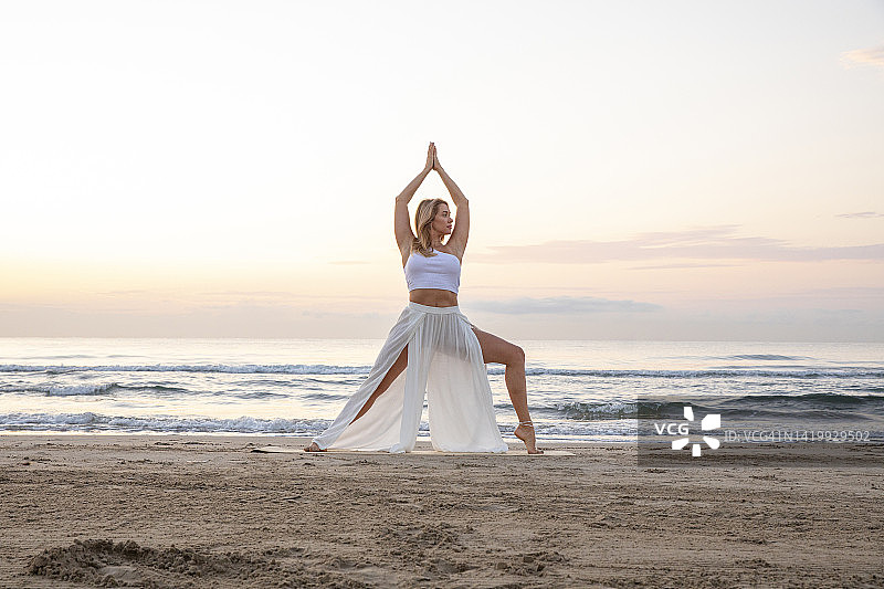 女人练习瑜伽，在日出时的海滩上冥想图片素材
