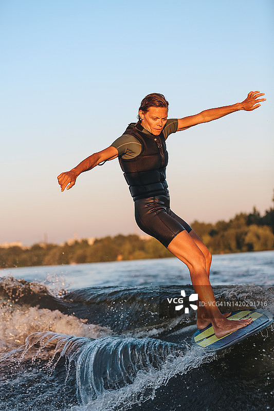 成人运动自信女子训练水上冲浪元素和保持水上滑板平衡图片素材