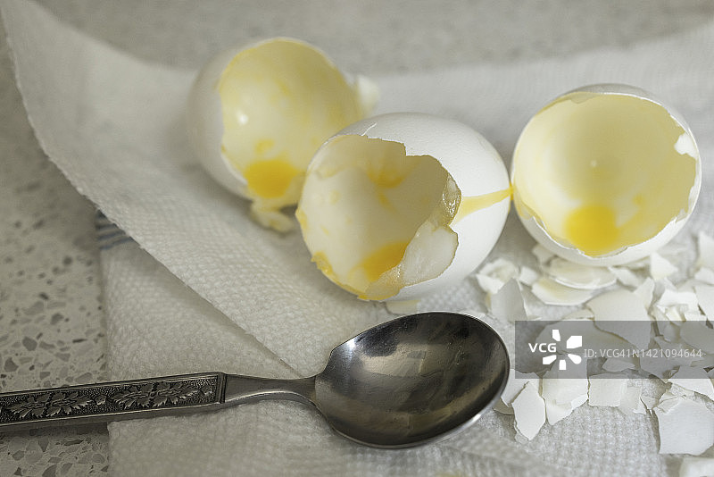 用汤匙在白色餐巾上舀空蛋壳。图片素材