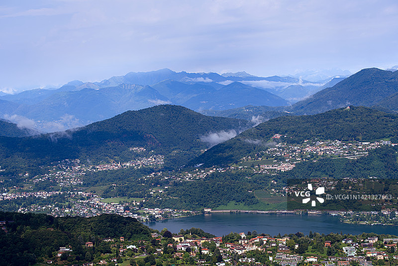 在一个多云的夏日，从当地的圣塞尔瓦托山，提契诺州，以穆扎诺湖和瑞士阿尔卑斯山为背景的风景。图片素材