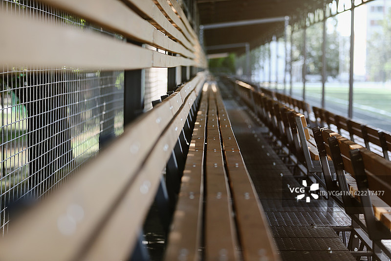 阳光明媚的夏日，户外运动场上的空木椅图片素材