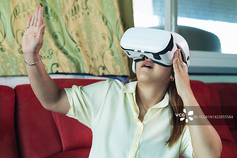 在家里玩虚拟现实眼镜和元宇宙内容的女人图片素材