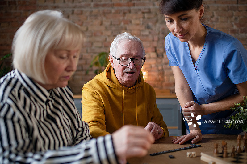 老人在敬老院玩棋盘游戏，护士正在和他们一起玩。图片素材